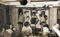 Michael Rudder (centre, in dark boob tube) in a crew show at sea, 1970s